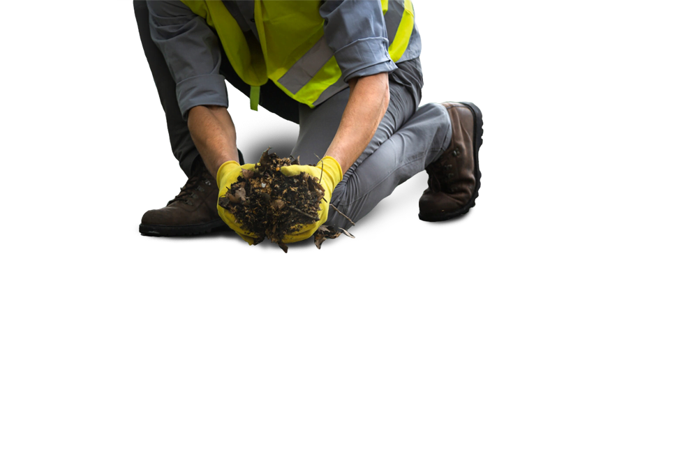 Worker in safety gear removing debris from a gutter, emphasizing professional gutter cleaning services for residential and commercial properties.