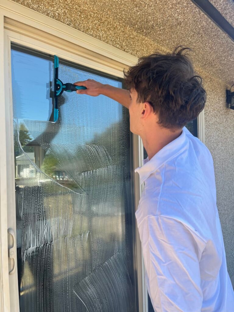 Frater Exterior Cleaning Services employee using a squeegee for window cleaning in Victoria and Langford - Frater Exterior Cleaning Services on Vancouver Island specializes in Roof Moss Removal and Treatment, Gutter Cleaning, Window Cleaning, Pressure Washing, House Washing as well as Commercial Exterior Cleaning Services.
